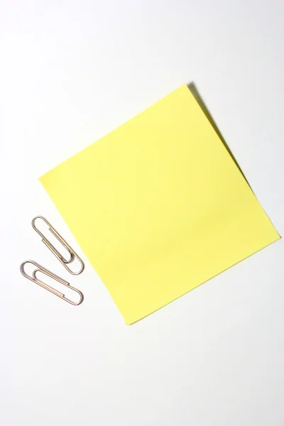 Yellow note with clip on white background — Stock Photo, Image