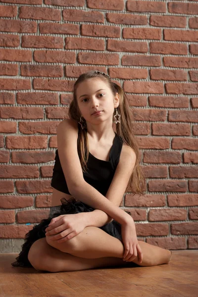 Dziewczyna w czarnym siedzi w pobliżu mur z cegły — Zdjęcie stockowe