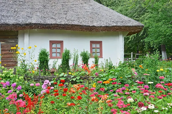 Cama de flores e cabana antiga — Fotografia de Stock