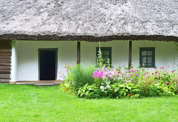 Flowerbed and ancient hut — Stock Photo, Image