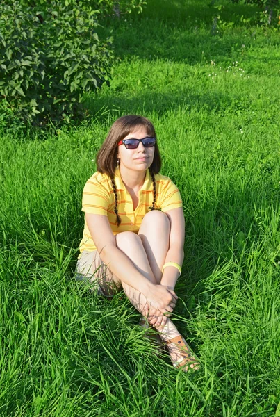 Mladá žena sedící na trávě — Stock fotografie