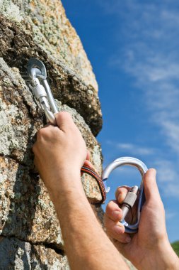 Two hands of climber fix equipment on rock clipart