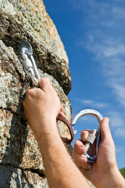 Twee handen van klimmer fix apparatuur op rock — Stockfoto