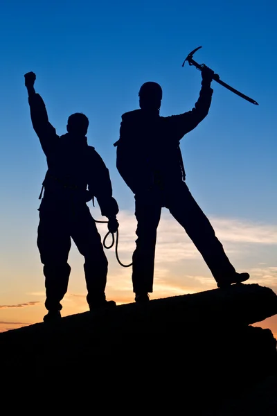 Silhouette of two climbers with hands up — ストック写真