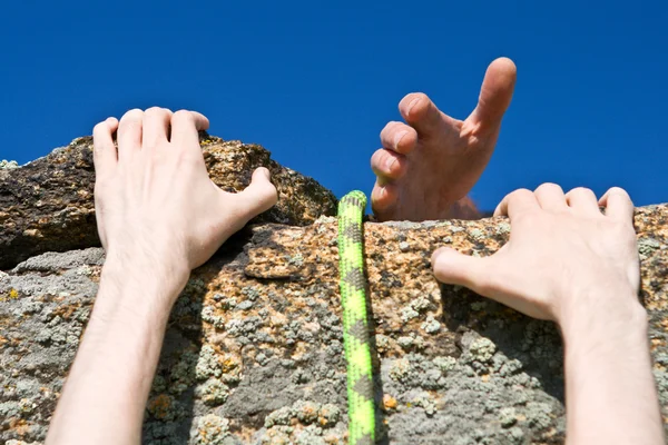 Rock klimmer bereiken voor handje partner. — Stockfoto