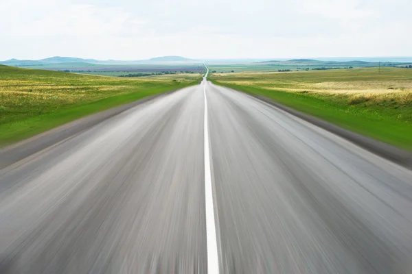 Estrada saindo no céu com grama verde na beira da estrada — Fotografia de Stock