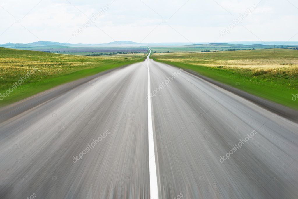 Highway leaving in the sky with green grass on roadside
