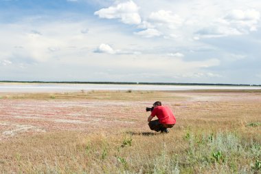 Video operator works on the bank of salty lake