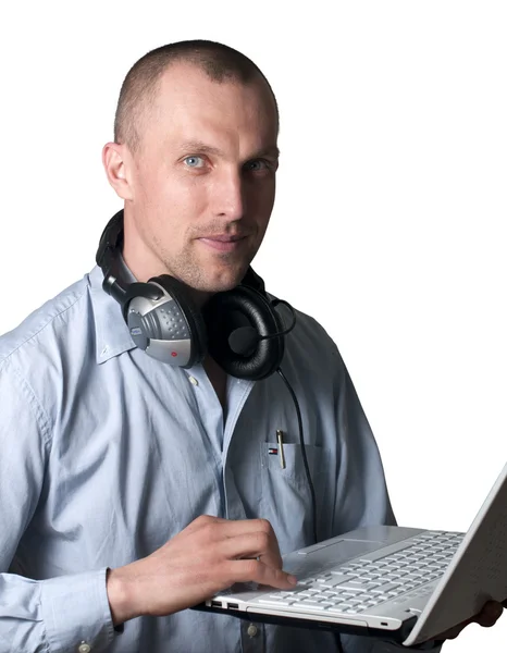 Een jonge man met hoofdtelefoon en een laptop — Stockfoto