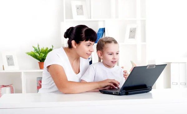 Mamá e hija están trabajando juntas para un portátil —  Fotos de Stock