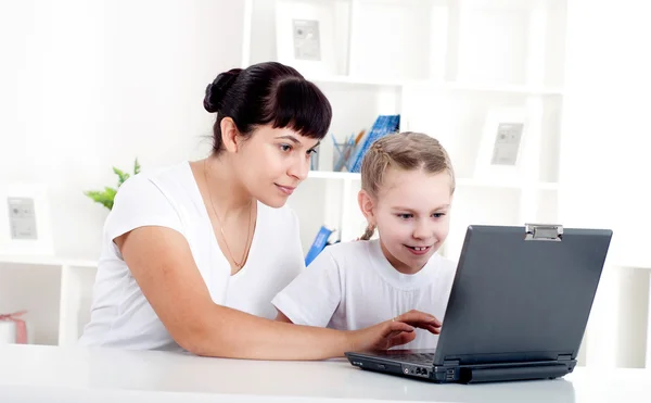 Mor og datter arbejder sammen for en bærbar computer - Stock-foto