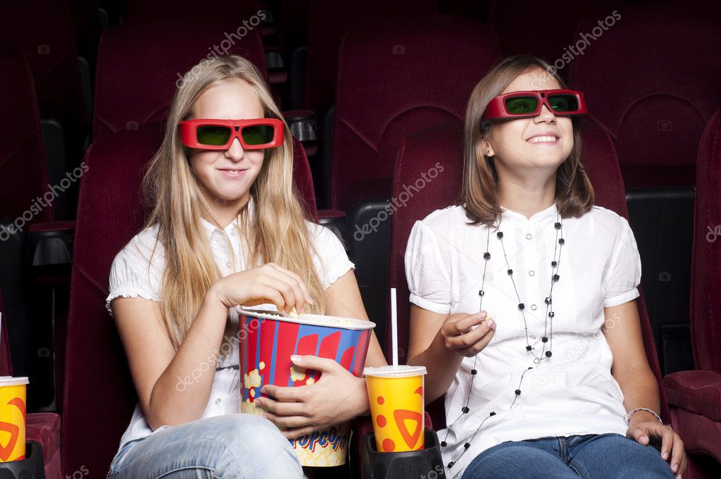 Two beautiful girls watching a movie at the cinema