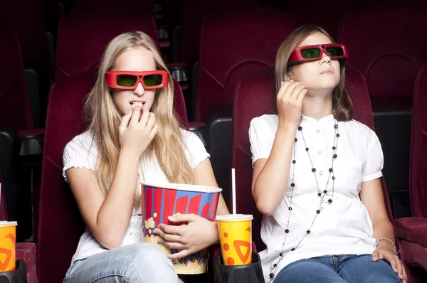 Zwei schöne Mädchen, die einen Film im Kino ansehen — Stockfoto