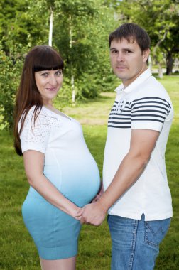 Man and a pregnant woman in the park clipart