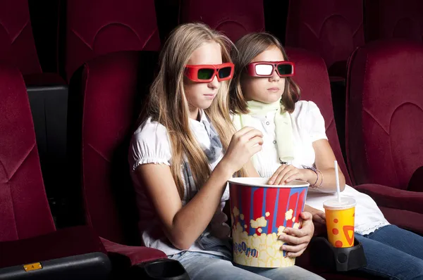 Две красивые девушки смотрят кино в кинотеатре Лицензионные Стоковые Изображения