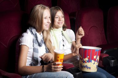 Two beautiful girls watching a movie at the cinema clipart