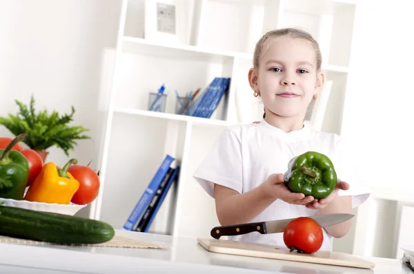 Vacker flicka i köket matlagning grönsaker — Stockfoto