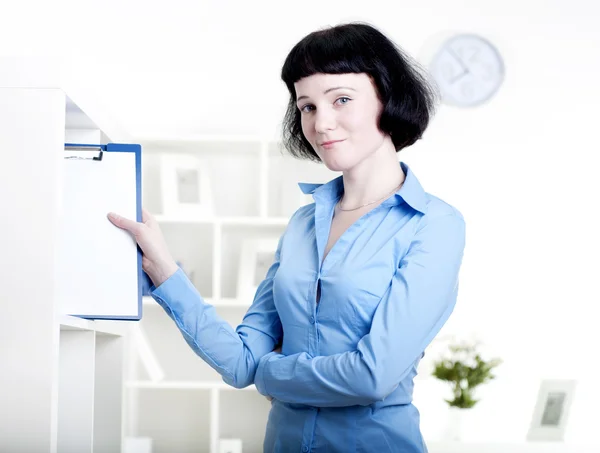 Mujer pone una tableta con documentos en un estante —  Fotos de Stock