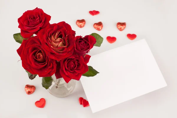 흰색 배경에 흰색 카드와 함께 빨간 장미 꽃다발 스톡 이미지