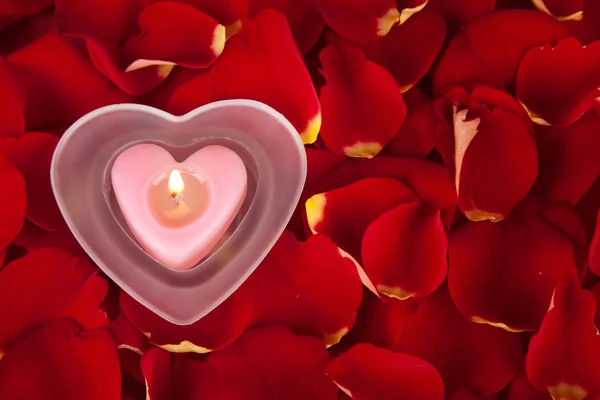 蜡烛在玫瑰花瓣上红色背景中 — 图库照片