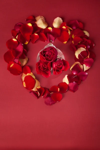Μπουκέτο με κόκκινα τριαντάφυλλα ένα υπόβαθρο των ροδαλών πετάλων Royalty Free Φωτογραφίες Αρχείου