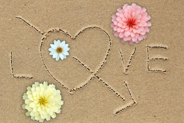 Η λέξη αγάπη με αγάπη σύμβολο και τα λουλούδια στην άμμο — Φωτογραφία Αρχείου