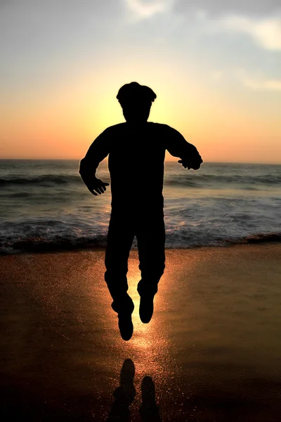 Un giovane adulto salta di sera su una spiaggia — Foto Stock