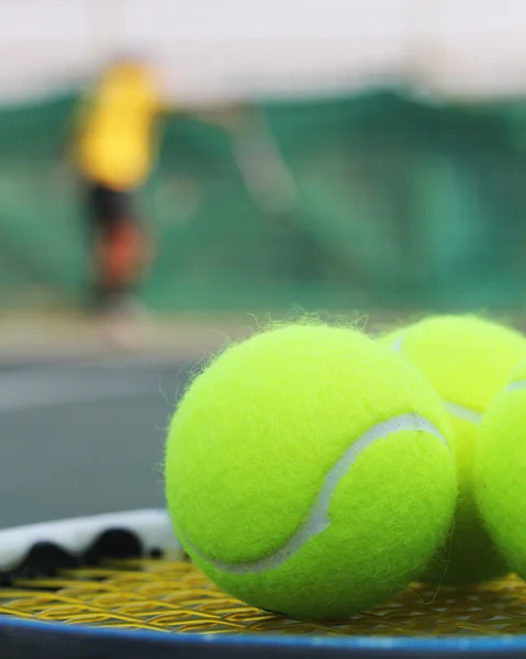 Palle da tennis sulla racchetta e una persona in background — Foto Stock