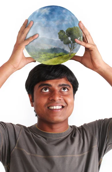 Молодой человек улыбается и держит мяч с экосистемой — стоковое фото