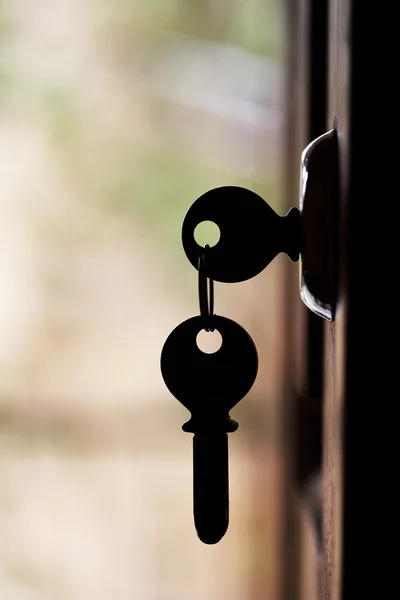 Silhueta de chaves de porta penduradas na porta aberta — Fotografia de Stock