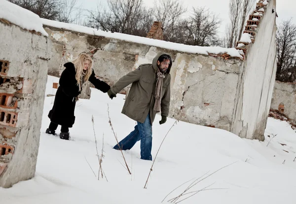 Casal sem-teto andando na neve de mãos dadas — Fotografia de Stock