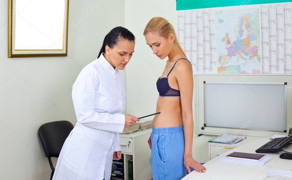 Ärztin in weißer Uniform untersucht den Körper der blonden Frau.