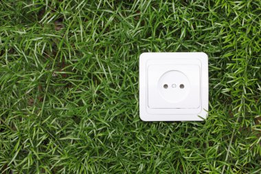 Electric power receptacle on a green grass background clipart