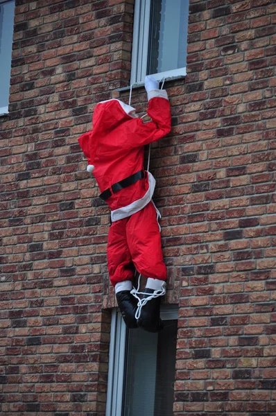 Santa claus wspinać się w oknie. — Zdjęcie stockowe