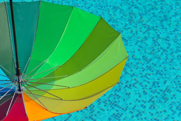 Colorful umbrella on a swimmingpool water background — Stock Photo, Image