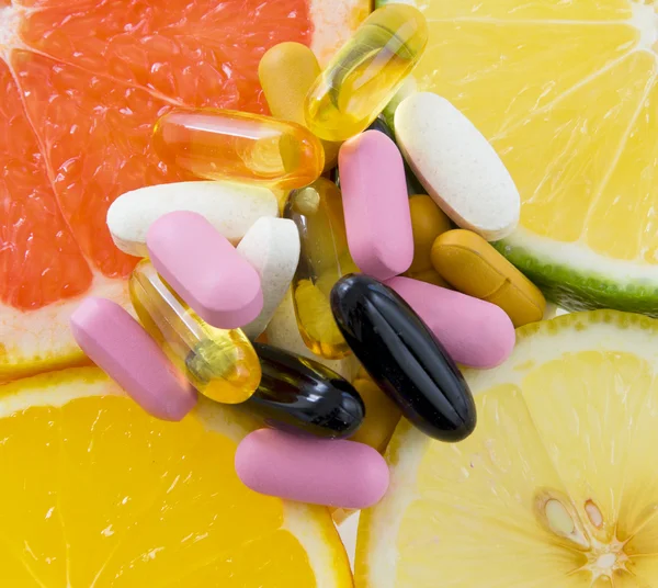 Gruppo di pillole su fette di frutta (arancia, limone, lime, uva da frutto — Foto Stock
