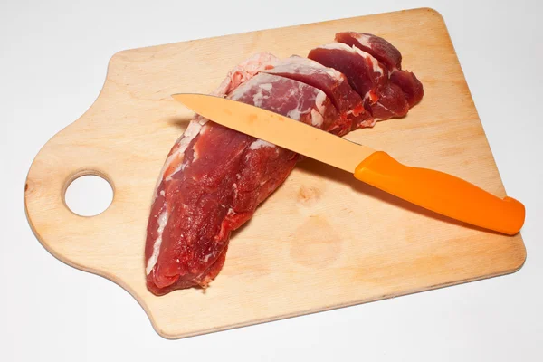Κρέας σε μια ξύλινη σανίδα που μαχαιρώθηκε σε λευκό φόντο — Φωτογραφία Αρχείου