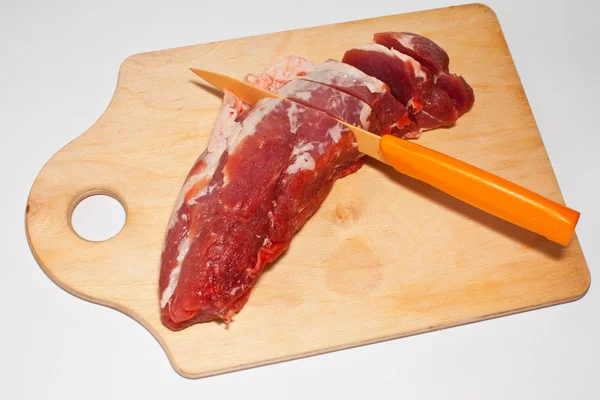 Κρέας σε μια ξύλινη σανίδα που μαχαιρώθηκε σε λευκό φόντο — Φωτογραφία Αρχείου