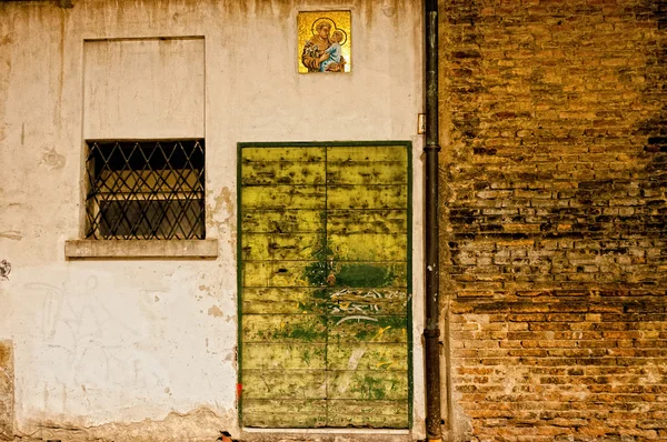 Texturou staré dveře a svatý obrázek na zdi v reggio emilia, Itálie — Stock fotografie