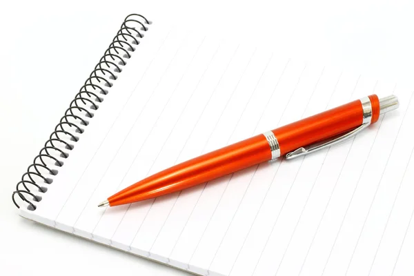 Блокнот с оранжевой шариковой ручкой — стоковое фото