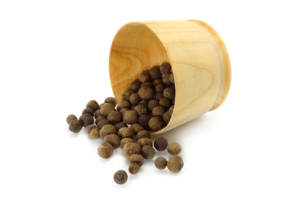 Seeds of allspice poured out from wooden bowl — Stock Photo, Image