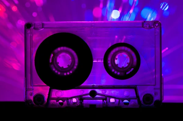 Transparentní kazeta páska a diskotéka světlo pozadí — Stock fotografie