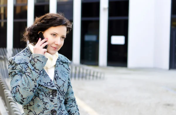 Retrato de una chica bonita con un teléfono móvil en el fondo de un edificio de negocios — Foto de Stock