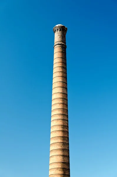 Iindustrial cihlový komín proti jasně modré obloze. — Stock fotografie