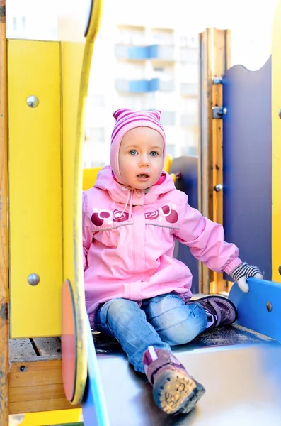 Menina sentada no slide no parque infantil . — Fotografia de Stock