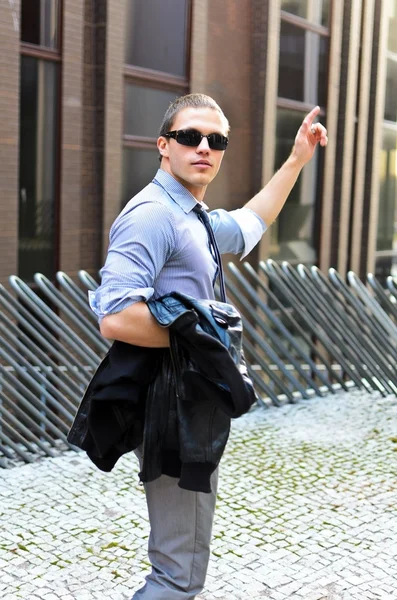 Porträtt av framgångsrik ung kille med jackan i handen mot urban bakgrund — Stockfoto