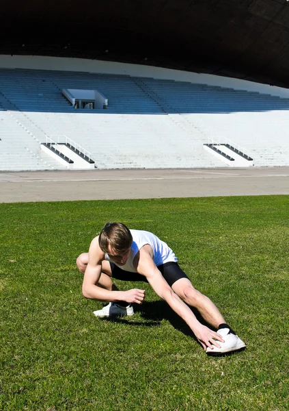 Runner at the city stadium warming and stretching — Stock Photo, Image