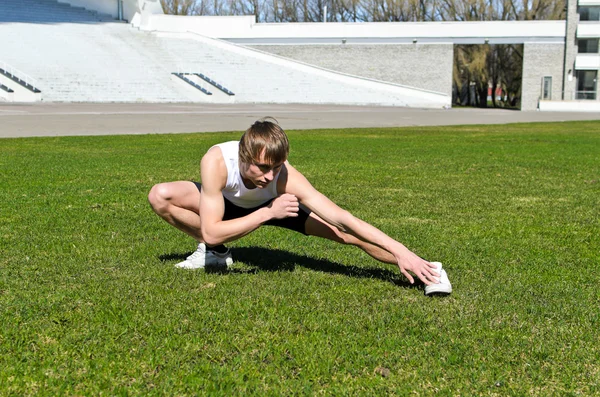 Runner at the city stadium warming and stretching — Stock Photo, Image