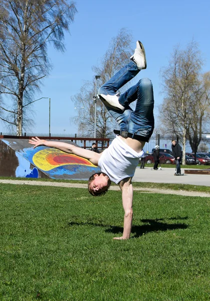 Breakdancer dělá odklápěcím na trávě. — Stock fotografie