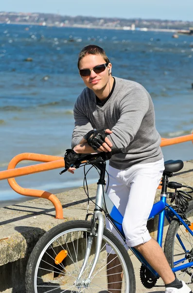 Porträt eines hübschen Mannes mit Fahrrad am Meer — Stockfoto